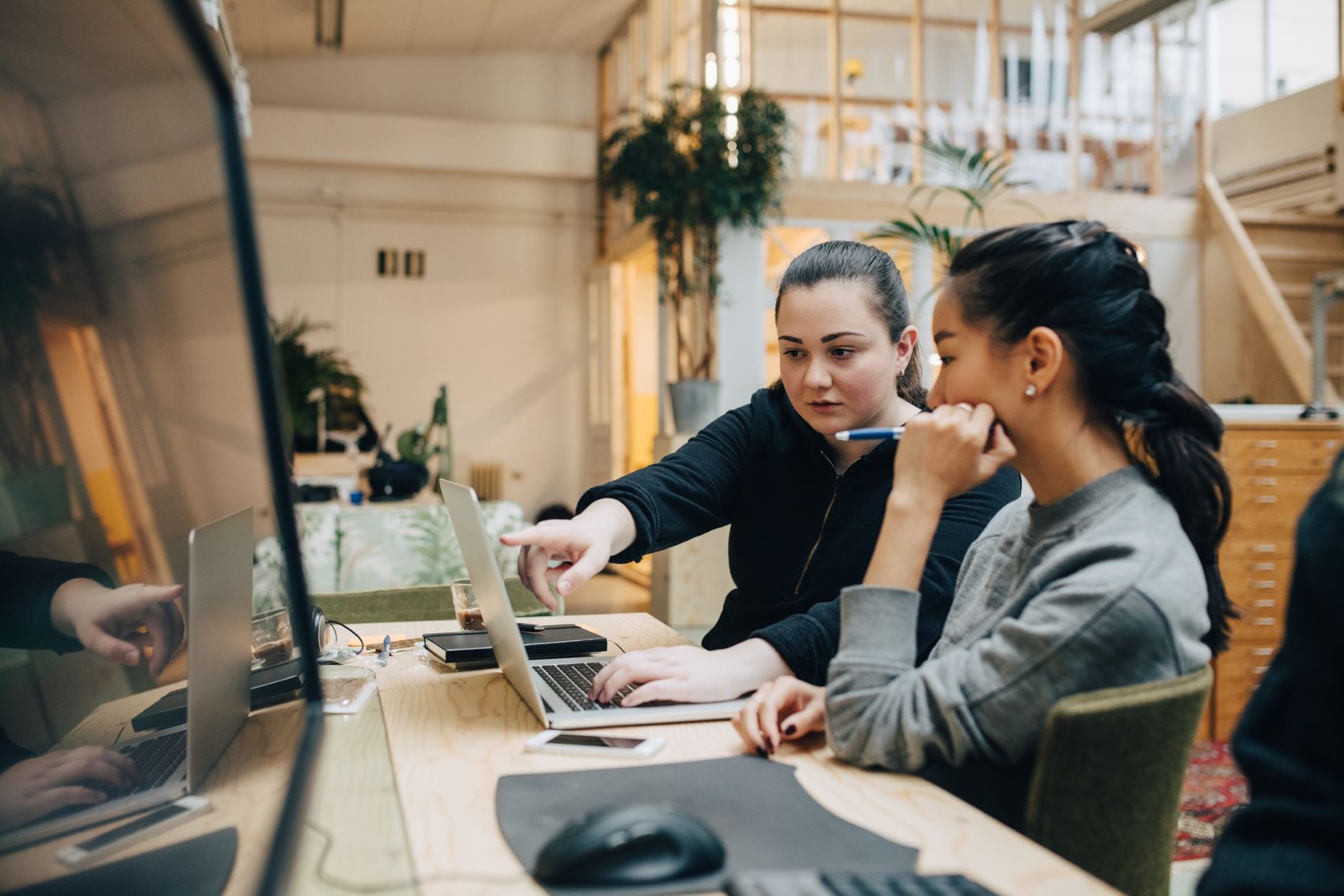 two people in a modern office pointing at the laptop