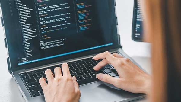 Hands of a woman typing code in a laptop