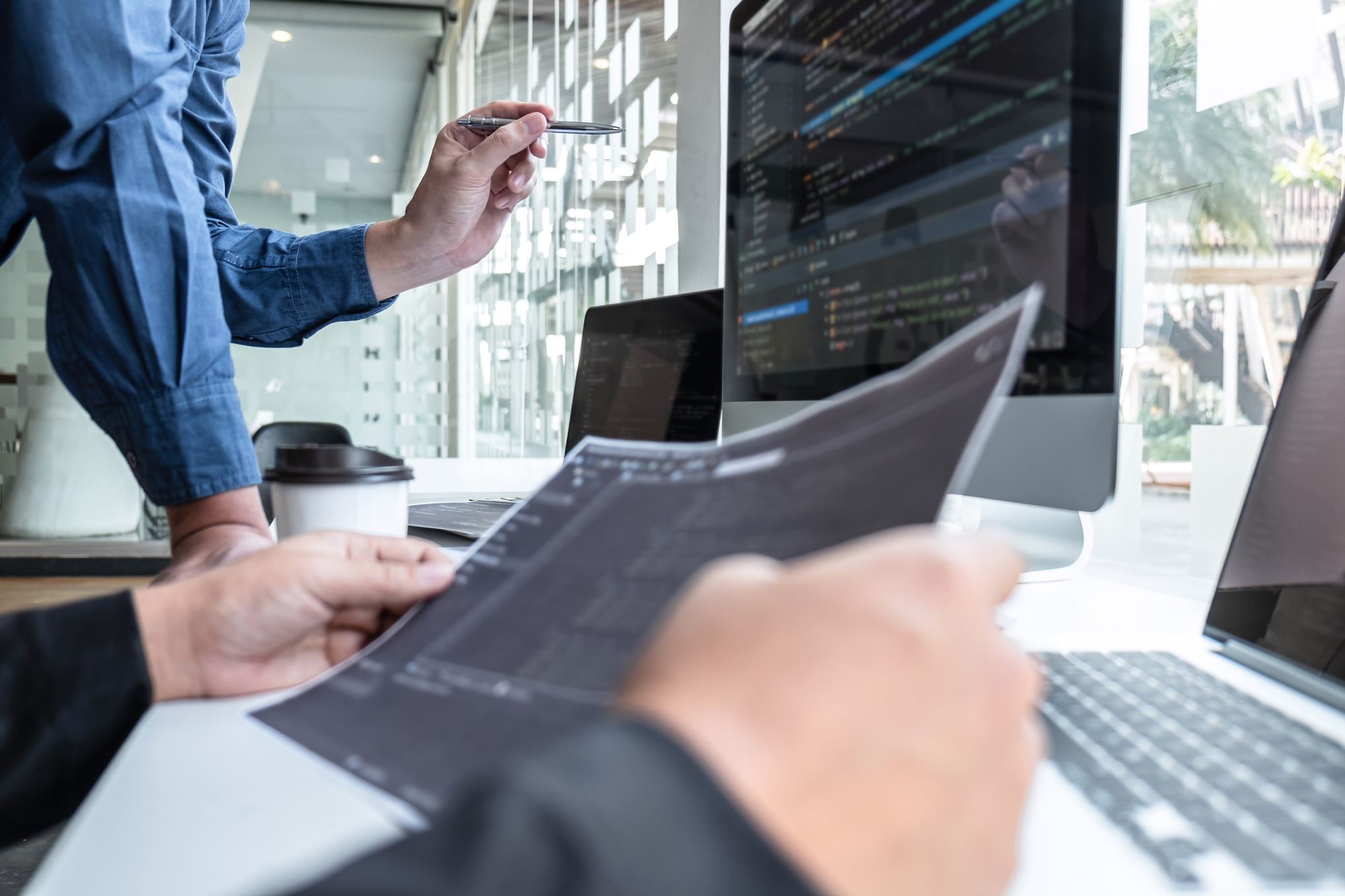 people looking at a computer and papers with graphs on it