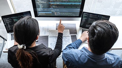 Man and woman working on multiple screens